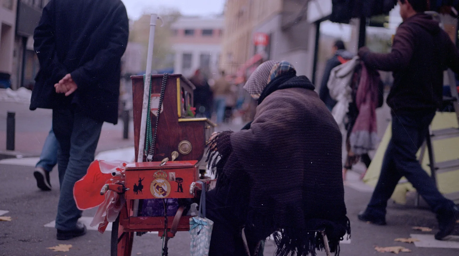 A barrel-organ player seen from behind, playing in the street at El Rastro de Madrid