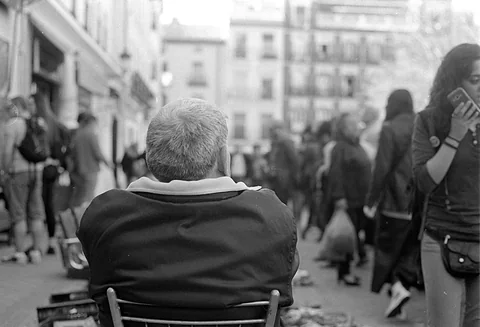 Un vendedor de espaldas en su silla, en El Rastro de Madrid