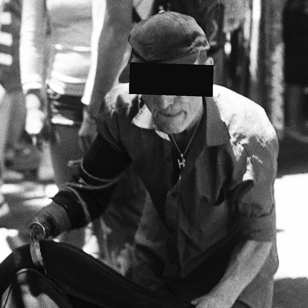 Un vendedor con gorra agachado sobre su género en El Rastro de Madrid