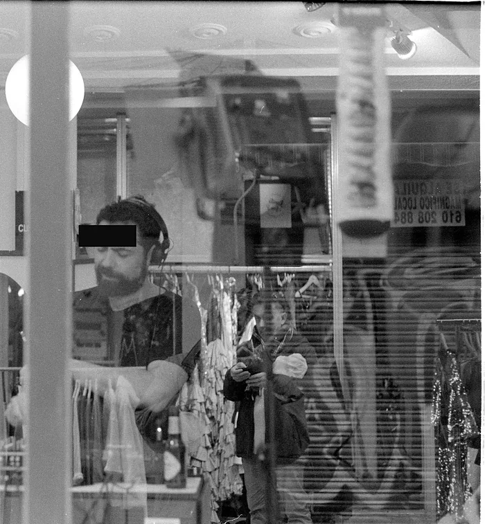 Un hombre con auriculares tras el escaparate de una tienda de El Rastro de Madrid