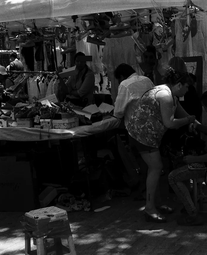 Un puesto de trastos con bolsos y zapatos colgados en El Rastro de Madrid